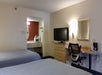 Two queen beds, desk, TV, and a single vanity mirror in a guest room.