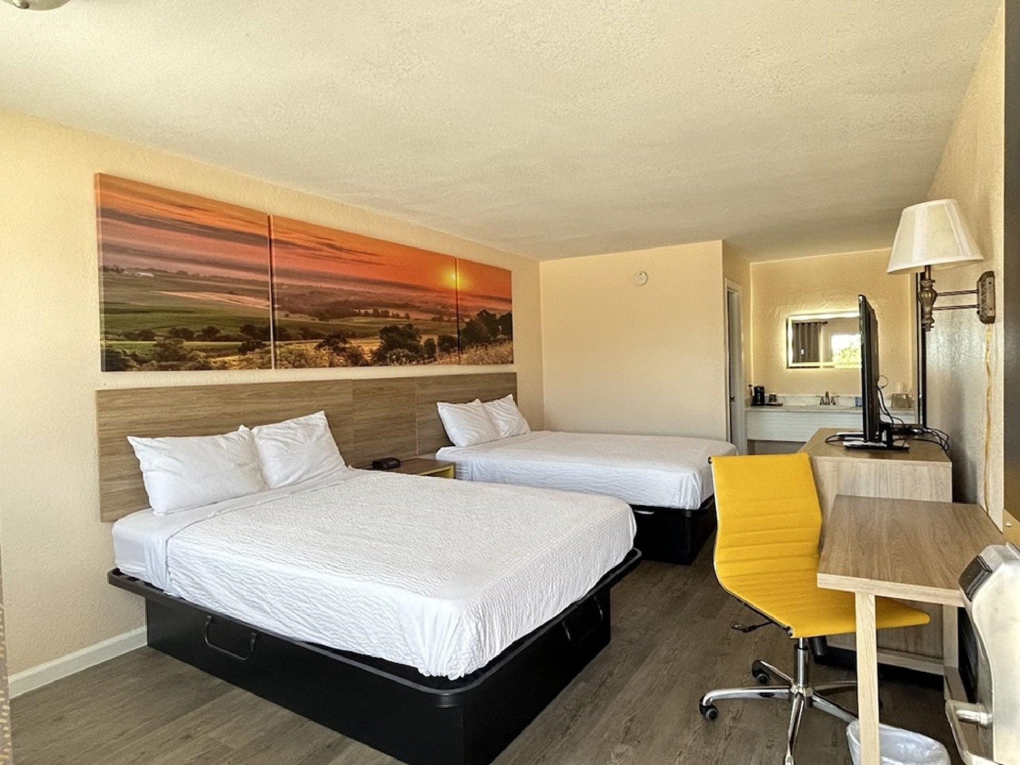 Guest room with two queen beds, desk, and flat-screen TV.