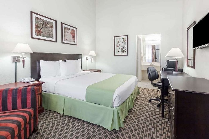 One queen bed, flat-screen TV, and a work desk inside a private suite.