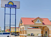 Exterior view of a Days Inn hotel with a red-tiled roof entrance, a sign with the Days Inn logo, and parked cars.