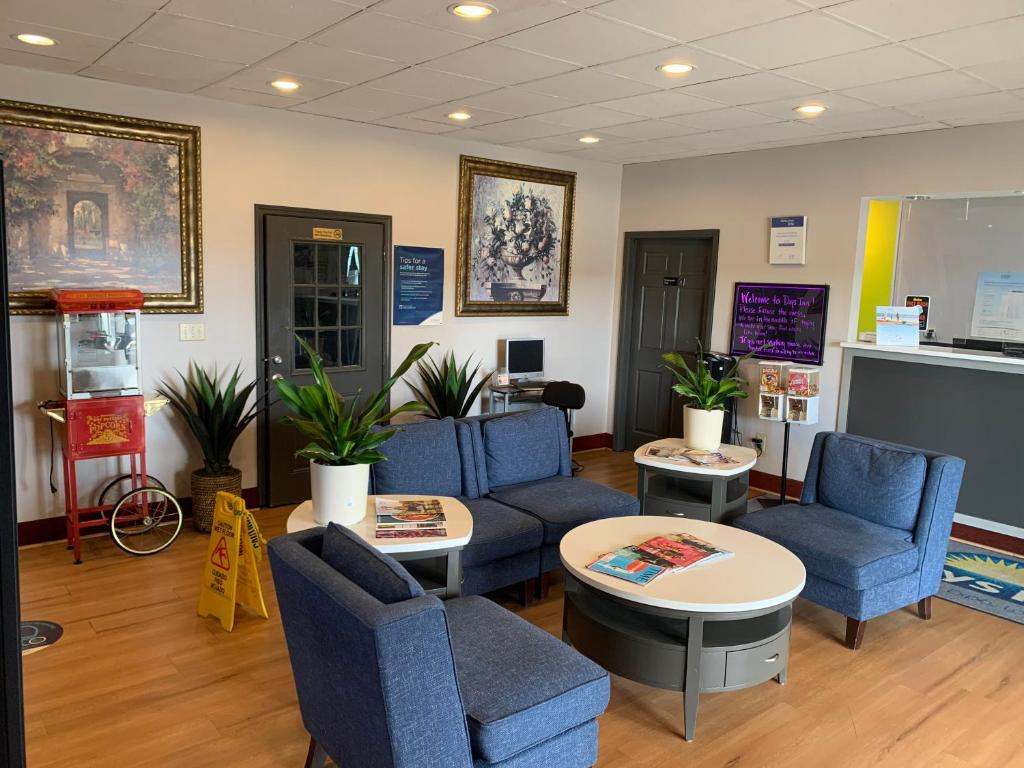 Lobby area with blue chairs, round tables, and potted plants. A popcorn machine and art hang on walls. Reception counter in background, with a computer station nearby.