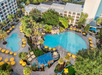 Aerial view of the serene pool are with two outdoor pools, a waterslide, lounge chairs and umbrellas.