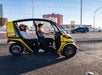 Two women riding in a yellow GoCar on a sunny day with the city of Las Vegas in the background.