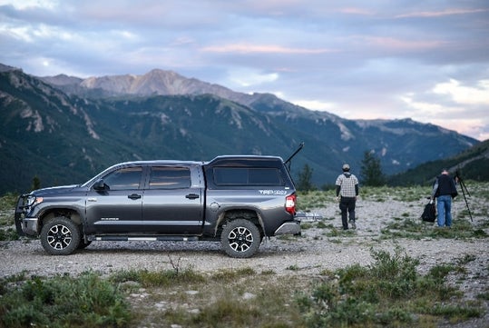 Two photographers standing to the right of the tour operator’s pickup truck/shuttle prepare to capture photos of Denali’s scenic mountain backdrop