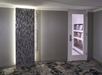 Entrance to a concierge lounge with a textured wall and a door featuring shelves visible through a window.