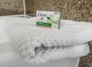 A white folded towel is placed on a bathroom surface next to a box of Dove cool moisture beauty cream bar.