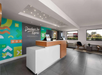 Modern hotel lobby with a reception desk, colorful wall art, and seating area. Large windows provide natural light. The name "Developer Inn Express" appears on the wall.