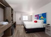 Guest room with one king bed, mini fridge, microwave, desk and chair.
