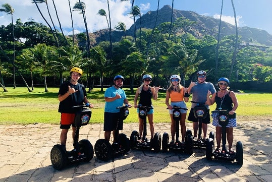 Group Posing on their segways in front of the Palm Trees and mountains on the Diamond Head Segway Tour, Honolulu Hawaii.