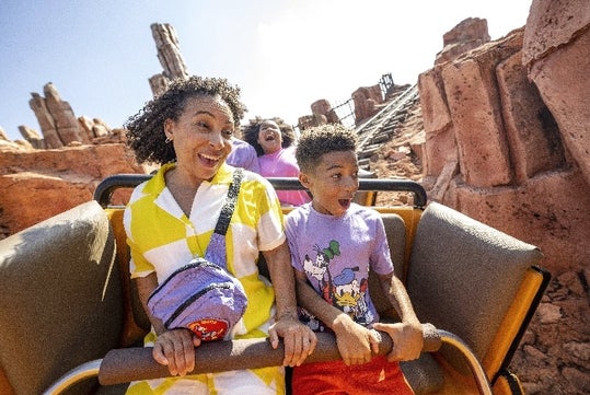 A family grins from ear to ear as they enjoy downhill thrills on a roller-coaster at Magic Kingdom® Park.