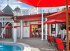 Poolside bar, dining tables with umbrellas and chairs next to the pool.