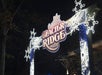 An illuminated Glacier Ridge sign with snowflake decorations is displayed at night, marking the entrance to an outdoor attraction.