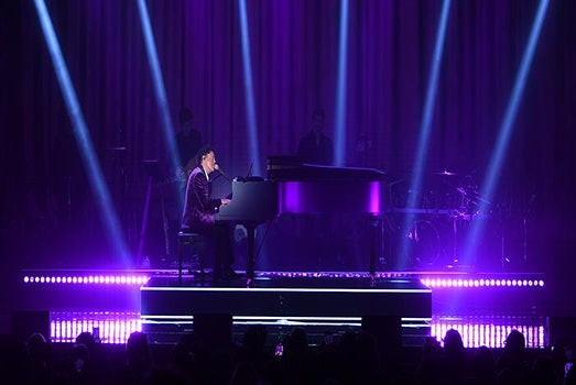 Donny Osmond singing on the stage while playing piano with purple lights shining behind him at Harrah’s in Las Vegas.