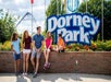 A family sitting on a brick wall in front of the sign for Dorney Park on a sunny day in Allentown, Pennsylvania.