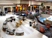 Spacious hotel lobby with modern seating, multiple TVs, a small indoor pond, and a snack area in the back.