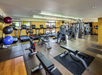 A gym with treadmills, exercise bikes, weight machines, benches, and stability balls.
