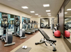 A modern gym with treadmills, ellipticals, a weight bench, exercise balls, and mirrors.