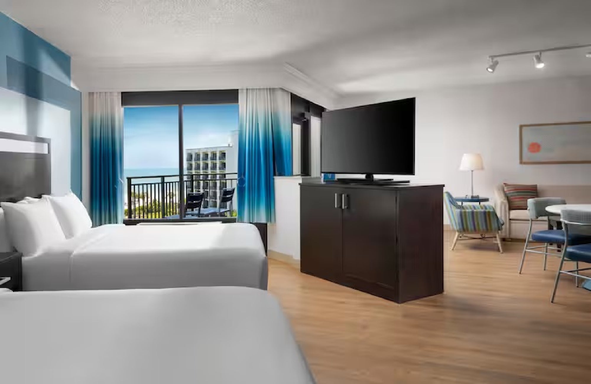 A suite with two queen beds, a large TV, and a seating area