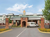 Hotel entrance with a covered driveway, a branded van, and brick pillars displaying the DoubleTree logo.