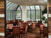 A dining room with dark wooden tables with matching chair and two walls made of glass at the Woodlands at DoubleTree by Hilton Hotel Flagstaff.