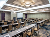 Meeting facility with long table setup, a podium and a white projector screen.