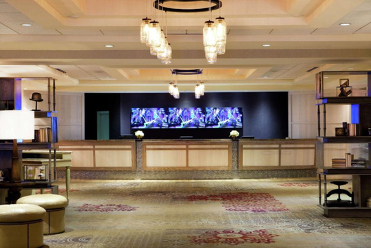 Front desk decorated with chandeliers and carpeted floors.