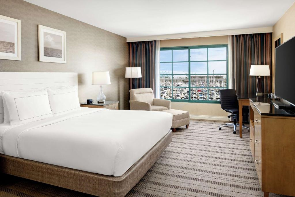 Guest room with one king bed, armchair, desk, flat-screen TV, and marina view.