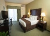 One king bed, bedside lamps, desk, TV, air condition, and seating area in a guest room.