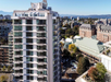 Aerial view of DoubleTree by Hilton hotel, surrounded by trees and neighboring buildings, with mountains and ocean visible in the background.