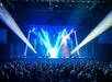 A theatre full of people watching Doug Gabriel perform with strobe lights covering the stage and shooting out into the audience.