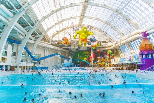 Wide shot of the wave pool full of people with DreamWorks in the background at DreamWorks Water Park at American Dream in Newark, New Jersey.