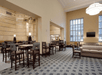 A large lobby with hightop dining tables on the left side, beige couches on the right, and a large windows on the far wall.