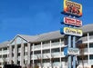 Exterior view of a hotel with signs for Duttons Family Theater, Dutton Deli & Desserts, and Dutton Inn against a clear blue sky.