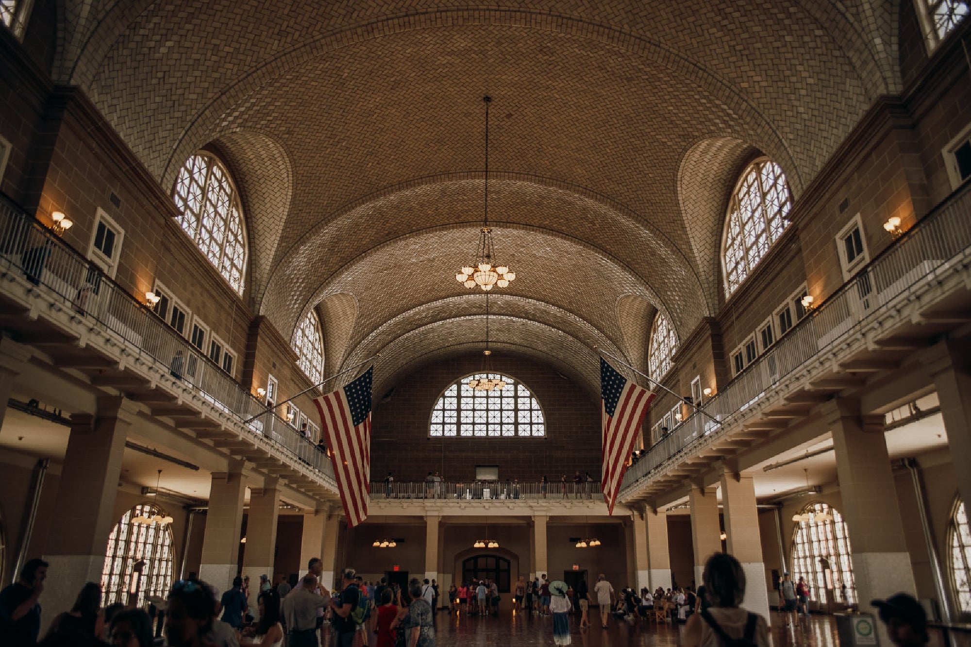 A large hall with arched ceilings, American flags, and a crowd of people.