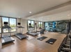 Modern gym with treadmills, stationary bike, weights, exercise balls, mats, and scenic window views.