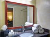 Bathroom with a countertop featuring a sink, rolled towels, toiletries, and a tissue box. A large mirror reflects the room and doorway.