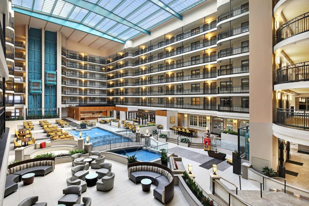 Interior of a spacious hotel atrium featuring multiple floors with balconies, a central pool, and seating areas.