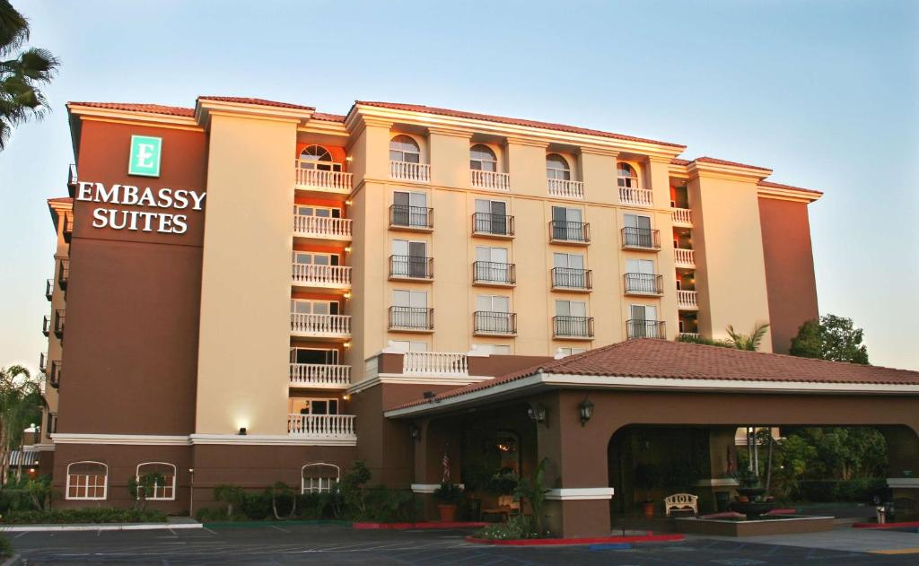 Exterior view of a multi-story Embassy Suites hotel with balconies and an entrance canopy.
