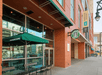 The exterior of a Starbucks with a small table with a green umbrella over it next to the Embassy Suites by Hilton Denver Downtown Convention Center.