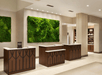 Hotel lobby with three wooden reception desks. A large, green moss wall is in the background. Shelves with items are visible on the right.