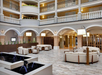 Wide view of a spacious hotel lobby featuring modern seating, fountain, tall arches, and multi-story open balconies with railings.