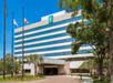 The front of the Embassy Suites with a semi-circle driveway with a covered entrance and several trees in the landscaping.