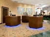 Four brown wooden receptions desks with computers at them and art on the wall behind them in the lobby of the Embassy Suites by Hilton Portland Airport.