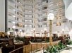 The interior of the Embassy Suites by Hilton Portland Airport, with a large white lobby with lots of plants and circular lamps, and open walkways on each floor showing the guest rooms.