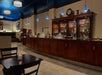 A long dark wooden bar with a large matching cabinet full of different types of alcohol behind it at the Embassy Suites by Hilton Portland Downtown.