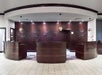 Three deep brown front desks with art carved into the wooden wall behind them at the Embassy Suites by Hilton.
