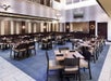 A large dining area with blue tiled floors and brown rectangle tables with black chairs at the Embassy Suites by Hilton.