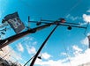 A flag with a skull-and-swords pirate emblem waves on a ship's mast against a blue sky with scattered clouds.