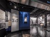 A modern exhibition space featuring a “Wonder of the Modern World” display, architectural images, blueprints, and photographs of urban buildings.