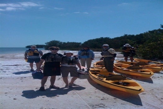 A group of people standing on the beach next to their kayaks in Chokoloskee Island, Florida